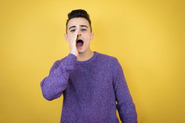 İzole edilmiş sarı arka planda genç beyaz bir adam el ele tutuşmuş bağırıyor ve çığlık atıyordu.