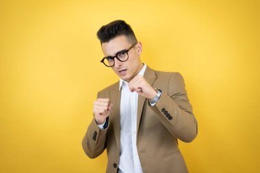 Genç iş adamı sarı arka planda. Yumruk yumruğa dövüşme, agresif ve öfkeli saldırı, tehdit ve şiddet.