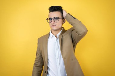 Soyutlanmış sarı bir geçmişi olan genç bir iş adamı bir elini kafasına koyup sanki bir şey unutmuş gibi gülümsüyordu.