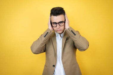 Soyutlanmış sarı arka planı olan genç bir iş adamı yorgun ve sıkılmış görünüyor.