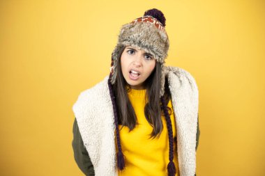 Sarı arka plan üzerinde yeşil bir palto ve şapka giyen genç ve güzel bir kadın şaşkınlık ve şaşkınlık dolu bir ifade, korku ve heyecan dolu bir yüz ile dehşete düşmüş ve şok olmuştu..