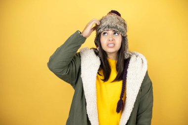 Sarı zemin üzerinde yeşil bir palto ve şapka giyen genç ve güzel bir kadın soru işaretlerini karıştırıyor. Şüpheyle karışık, kafa kafaya düşünerek.