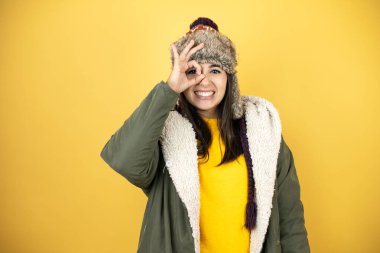 Sarı arka planda yeşil ceketli, şapkalı genç ve güzel bir kadın gülümseyen yüzüyle, gözleriyle parmaklarından bakarak şok oluyor.