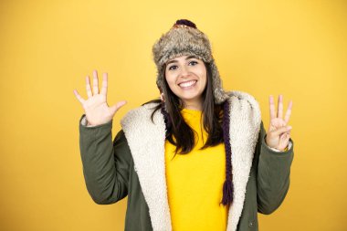 Sarı arka planda yeşil ceketli ve şapkalı güzel bir kadın sekiz numaralı parmaklarıyla gülümseyerek kendinden emin ve mutlu bir şekilde onu işaret ediyor.