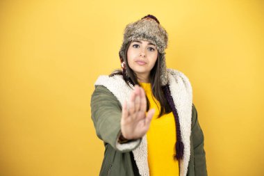 Sarı arka planda yeşil ceketli ve şapkalı güzel bir kadın ciddi ciddi şarkı söylemeyi kesiyor..