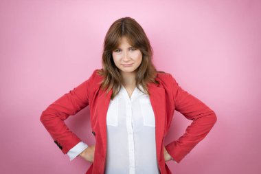 Soyutlanmış pembe arka planda genç bir iş kadını. Kuşkucu ve gergin. Yüzünde tasvip etmeyen bir ifade.