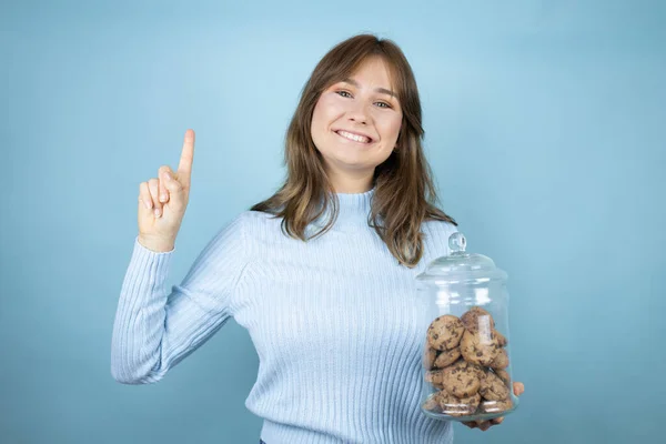 Young Beautiful Woman Holding Chocolate Chips Cookies Jar Isolated Blue — Stock Photo, Image