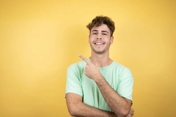 Sarı Arka Planda Yeşil Bir Tişört Giyen Yakışıklı Adam Gülümsüyor — Stok fotoğraf