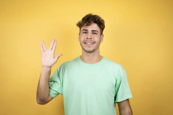 Hombre Guapo Vistiendo Una Camiseta Casual Verde Sobre Fondo Amarillo — Foto de Stock