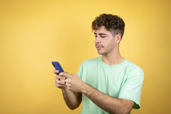 Bărbat Frumos Purtând Tricou Verde Casual Fundal Galben Texting Telefonul — Fotografie, imagine de stoc