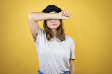 Fransız tarzı giyinen güzel beyaz bir kız. İzole edilmiş sarı arka planda beresi var. Gözleri kollarıyla neşeli ve komik gülümsüyor. Kör kavram.