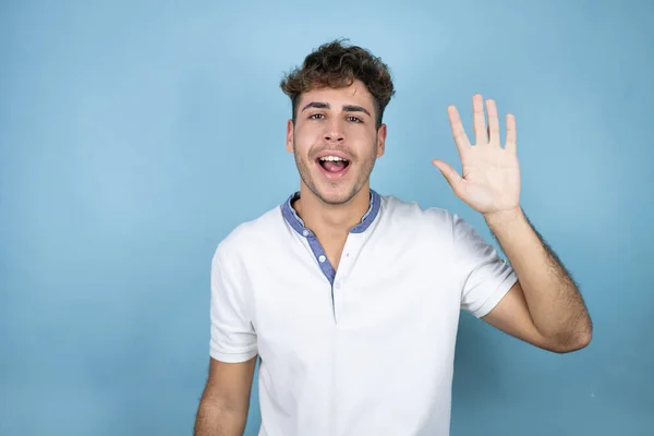 Junger Gutaussehender Mann Trägt Ein Weißes Shirt Über Blauem Hintergrund — Stockfoto