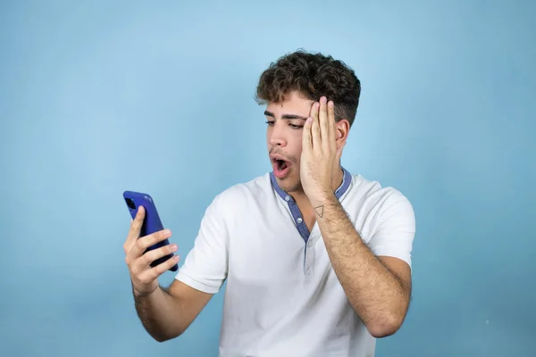Junger Gutaussehender Mann Weißem Shirt Vor Blauem Hintergrund Plaudert Telefon — Stockfoto