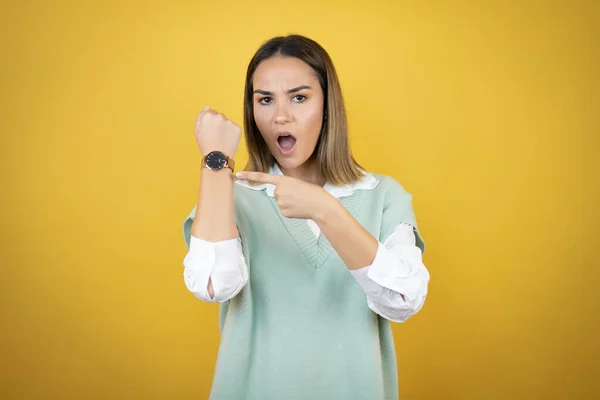 Mooie Jonge Vrouw Staan Gele Achtergrond Verbaasd Wijzend Haar Horloge — Stockfoto