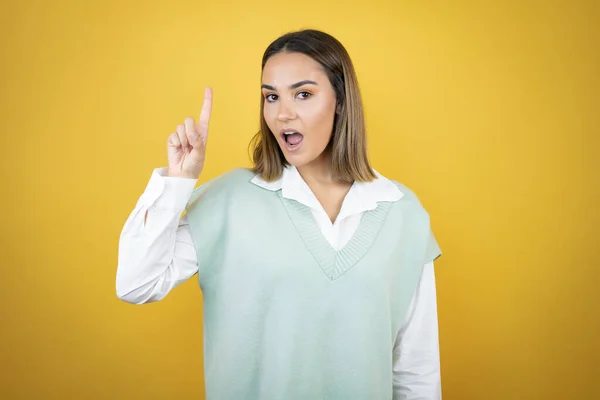 Muito Jovem Mulher Sobre Fundo Amarelo Surpreso Pensando Com Dedo — Fotografia de Stock