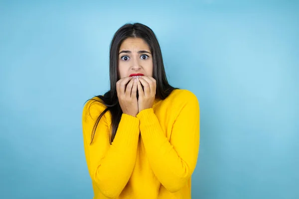 孤立した青の背景の上に黄色のセーターを着て若い美しい女性は 口の爪をかむ上で手で強調し 緊張している 不安の問題 — ストック写真