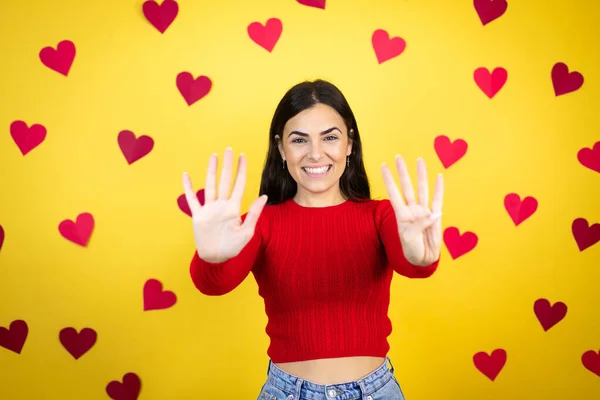 Молодая Белая Женщина Жёлтом Фоне Красными Сердцами Показывающая Пальцами Номер — стоковое фото