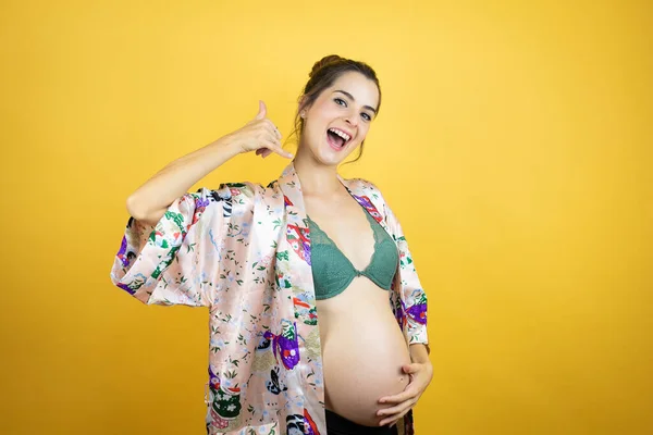 Genç Güzel Bir Kadın Hamile Sarı Arka Planda Pijama Giyiyor — Stok fotoğraf