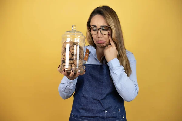 Young Hispanic Woman Wearing Baker Uniform Holding Cookies Jar Depressed — Stock Photo, Image