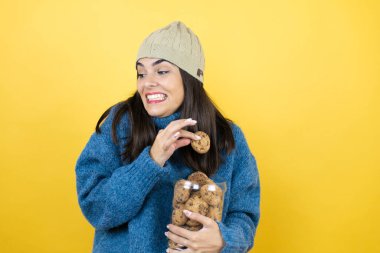 Mavi süveter ve yün şapka giyen, elinde çikolata parçacıklı kurabiye kavanozu tutan genç ve güzel bir kadın kendini suçlu hissedip kurabiye alıyor.