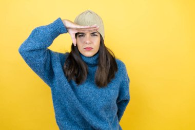 Mavi bir süveter ve yün şapka giyen genç ve güzel bir kadın çok mutlu ve tebessüm ediyor. arama kavramı.