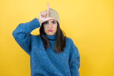 Mavi süveter ve yün şapka giyen genç ve güzel bir kadın. Alnında parmakları olan insanlarla dalga geçiyor. Ezik hareketler yapıyor, alay ediyor..