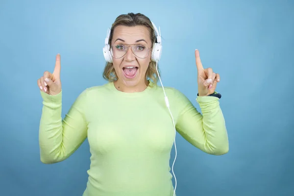 Νεαρή Καυκάσια Γυναίκα Ακούγοντας Μουσική Χρησιμοποιώντας Ακουστικά Πάνω Από Μπλε — Φωτογραφία Αρχείου