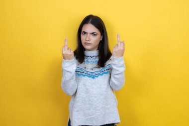 Young caucasian woman wearing casual sweater over yellow background showing middle finger doing fuck you bad expression, provocation and rude attitude. screaming excited