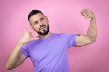 Pembe arka plan üzerine gündelik tişört giyen genç yakışıklı adam bana elleriyle jest yapıyor.