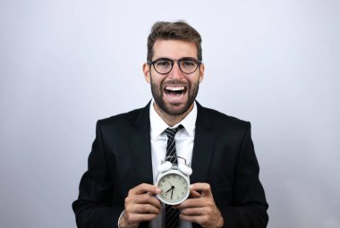 Takım elbiseli genç bir iş adamı bağırıyor ve korkuyor, elinde bir saat var.