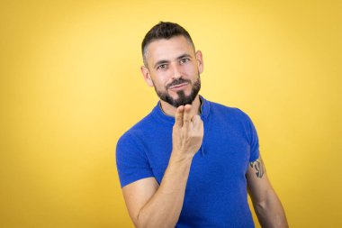 Sarı arka planda mavi polo tişörtlü yakışıklı bir adam. Kameraya bakıyor ve havada öpüşüyor. Güzel ve seksi. Aşk ifadesi.