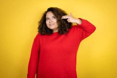 Sarı arka planda kırmızı kazak giyen Afro-Amerikalı genç bir kadın kendini ve parmaklarını silah gibi göstererek vurarak ve öldürerek intihar etti..