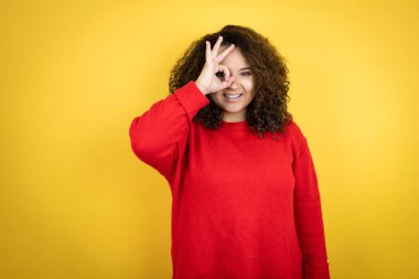 Sarı arka planda kırmızı süveter giyen Afro-Amerikalı genç bir kadın gülümseyen yüzüyle, gözleriyle parmaklarının arasından bakarken şok olmuştu.