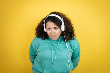 Genç Afrikalı Amerikalı kız spor kıyafetleri giyiyor ve kulaklık takıyor. Korkuyor ve şok geçiriyor..