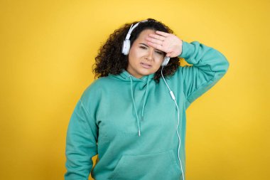 Genç Afrikalı Amerikalı kız spor kıyafetleri giyiyor ve kulaklık kullanıyor. Hastalık, ateş, grip ve virüs için alnına dokunuyor.