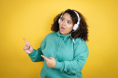 Genç Afrikalı Amerikalı kız spor kıyafetleri giyiyor ve kulaklık takıyor.