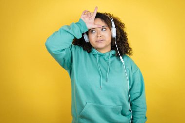 Genç Afrikalı Amerikalı kız spor kıyafetleri giyiyor ve kulaklık takıyor. Alnında parmakları olan insanlarla dalga geçiyor. Ezik hareketler yapıyor, alay ediyor ve hakaret ediyor..