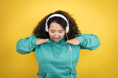 Spor kıyafetleri giyen, kulaklık takan ve elleri ağızda bağırarak bağıran Afrikalı genç bir Amerikalı kız.