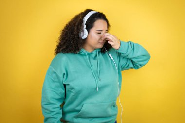 Genç Afrikalı Amerikalı kız spor kıyafetleri giyiyor ve kulaklık takıyor. Kokuşmuş ve iğrenç bir koku alıyor. Dayanılmaz bir koku.