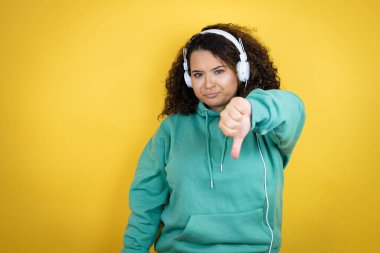 Genç Afrikalı Amerikalı kız spor kıyafetleri giyiyor ve kızgın yüzlü kulaklıklar takıyor.