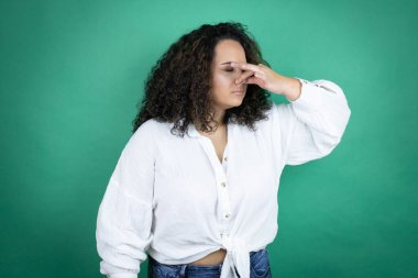 Genç Afro-Amerikalı kız yeşil arka planda beyaz gömlek giyiyor. Kokuşmuş ve iğrenç bir koku alıyor. Dayanılmaz bir koku.