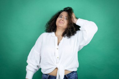 Beyaz tişörtlü, yeşil arka planda genç Afrikalı Amerikalı bir kız bir elini kafasına koyup sanki bir şey unutmuş gibi gülümsüyordu.