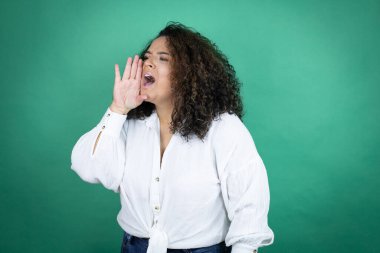 Beyaz tişörtlü, yeşil arka planda genç Afrikalı Amerikalı kız avaz avaz bağırıyor ve avaz avaz bağırıyor.