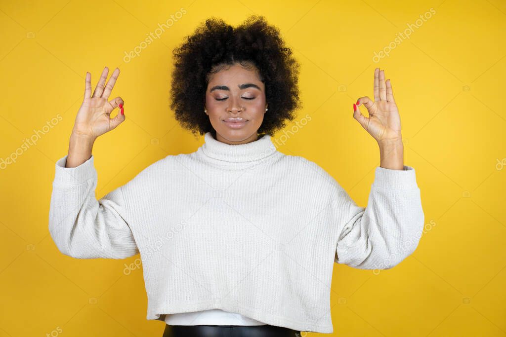 African american woman wearing casual sweater over yellow background relax and smiling with eyes closed doing meditation gesture with fingers