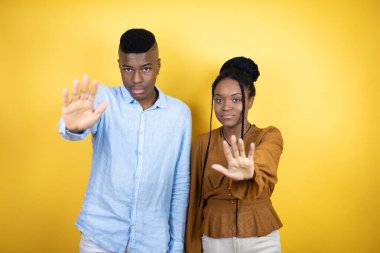 Sarı arka planda duran genç Afro-Amerikan çift güzel, güzel kadın, güzel, siyah saç, mavi arka plan, beyaz ırk