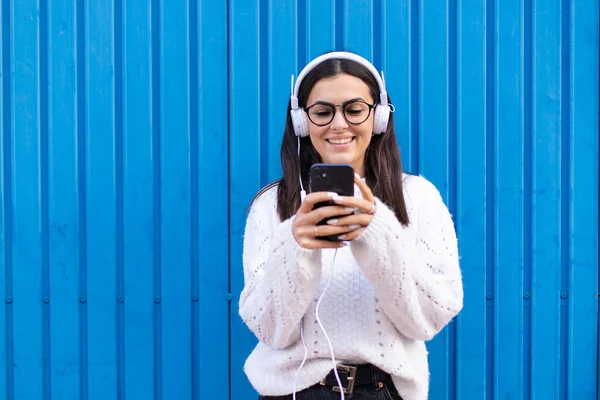 Young brunette woman smiling happy using smartphone and headphones at the city.