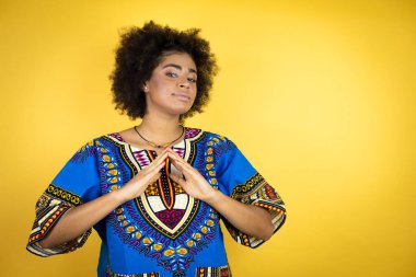 Sarı arka planda Afro-Amerikalı kadınlar ellerini birleştirip gülümseyerek rahat ve neşeli gülümsüyor. Başarı ve iyimser