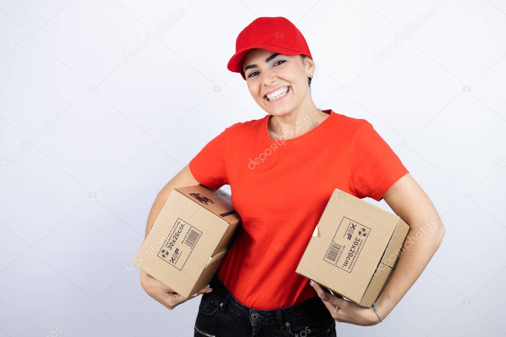 Young beautiful woman wearing courier uniform holding delivery packages with a happy face standing and smiling with a confident smile showing teeth