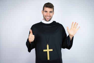 Beyaz arka plan üzerinde duran İspanyol üniformalı genç adam altı numaralı parmaklarıyla gülümseyerek kendinden emin ve mutlu görünüyor.