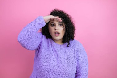 Genç, güzel bir kadın pembe arka planda rahat bir süveter giyiyor çok mutlu ve tebessüm ediyor. arama kavramı.